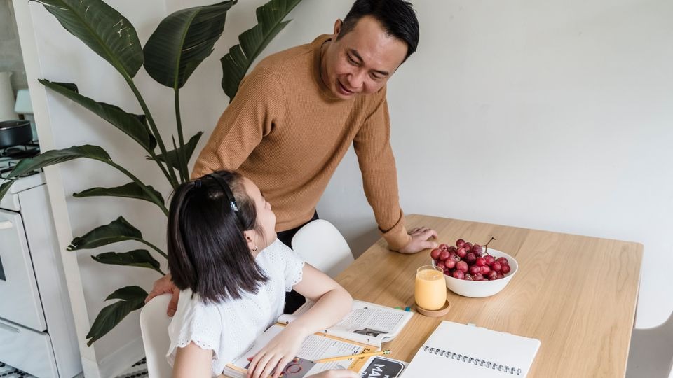 Father helping his daughter with homework in the evening while managing recovery and family responsibilities