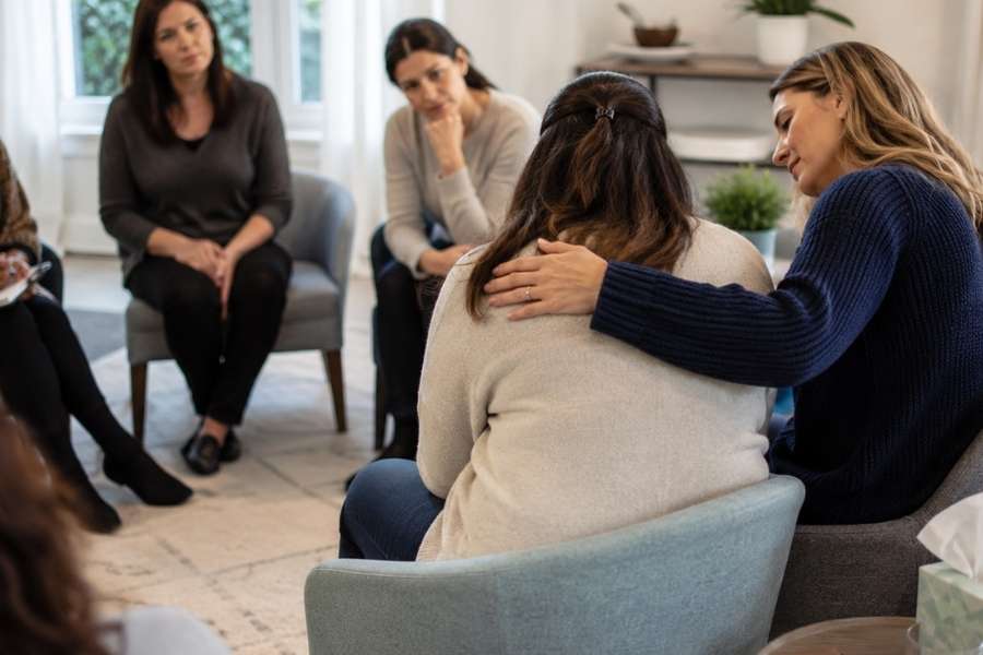 women in a women's group therapy session relive their trauma and past experiences with support.
