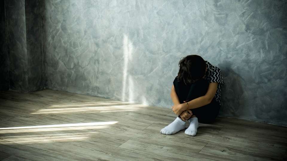 Alcohol-Induced Psychosis experienced by a woman sitting on the floor.